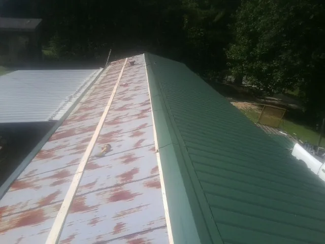 Old rusted panels beside newly installed green metal roofing — Wind Damage Roof Repair by Roofing Brothers in Mound City
