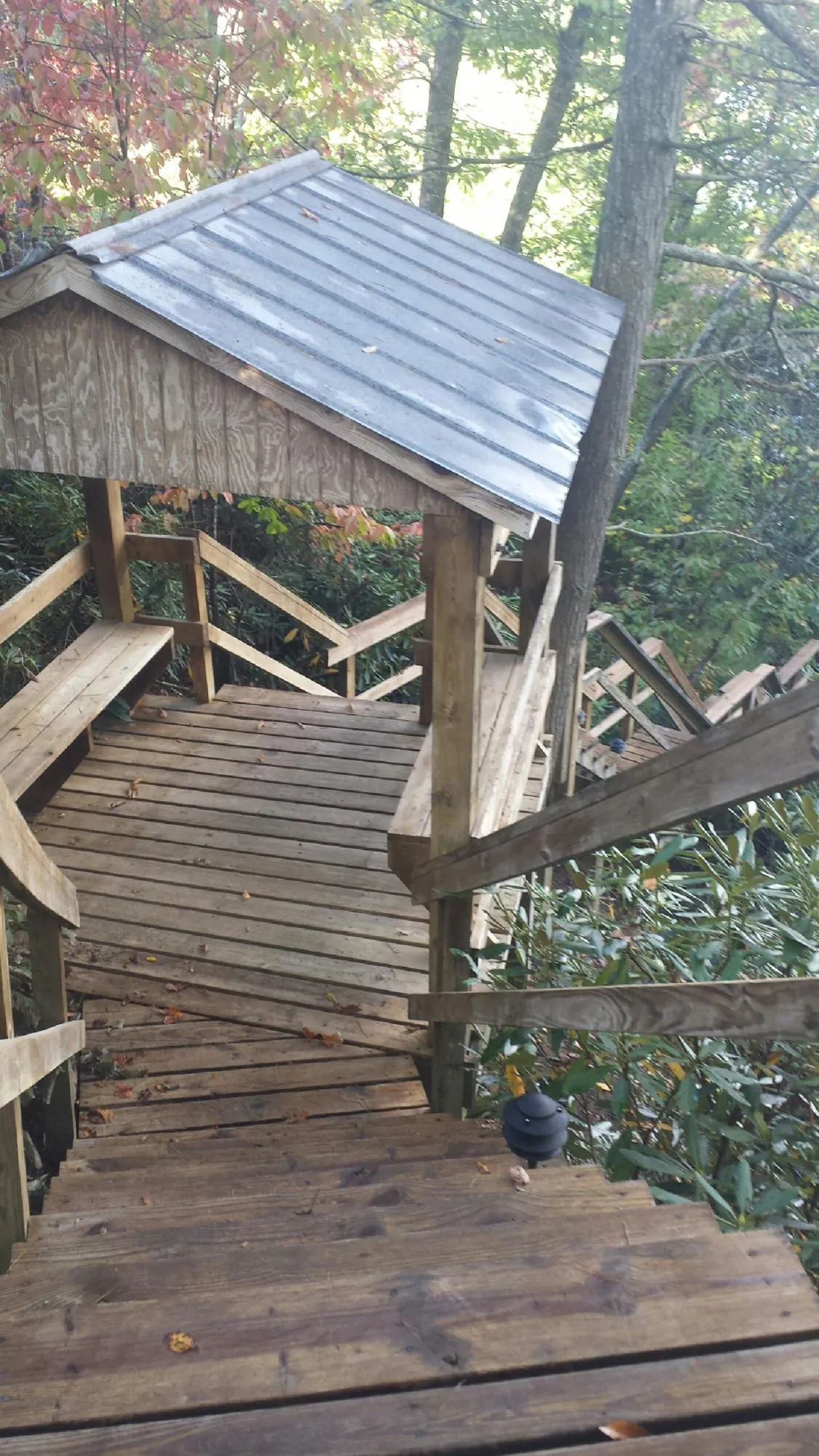 Metal roofed shelter over wooden steps on a wooded walkway — Skylight Repair & Installation work by our crew in Mound City
